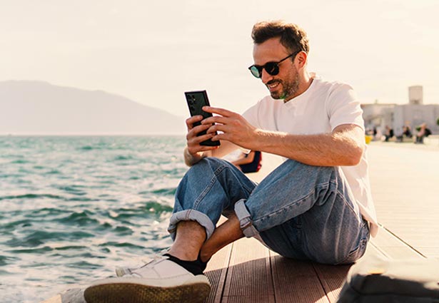 Person sitting on dock looking at their phone