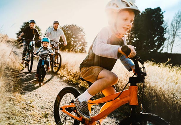 Kid riding bike with family following